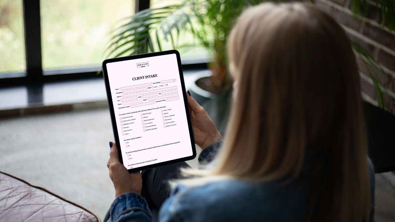 Client completing a Glow Forms digital client intake form on a tablet while seated in a salon lounge.
