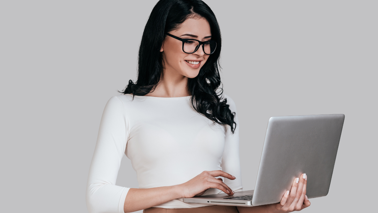 Salon owner in glasses using a laptop, reviewing Glow Forms client records and digital consent forms.