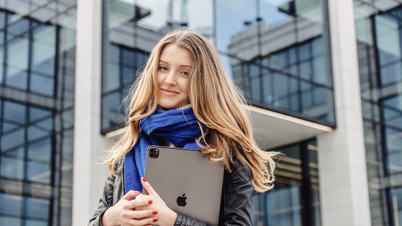 Mobile beauty therapist holding an iPad outside a client location, ready to review Glow Forms consent and treatment notes on the go.