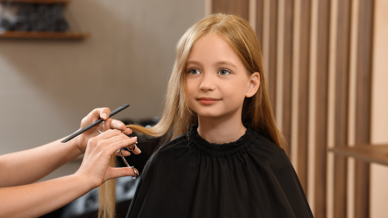 Young client getting a haircut at a salon while a stylist trims her hair—illustrates under-18 services with required guardian consent.