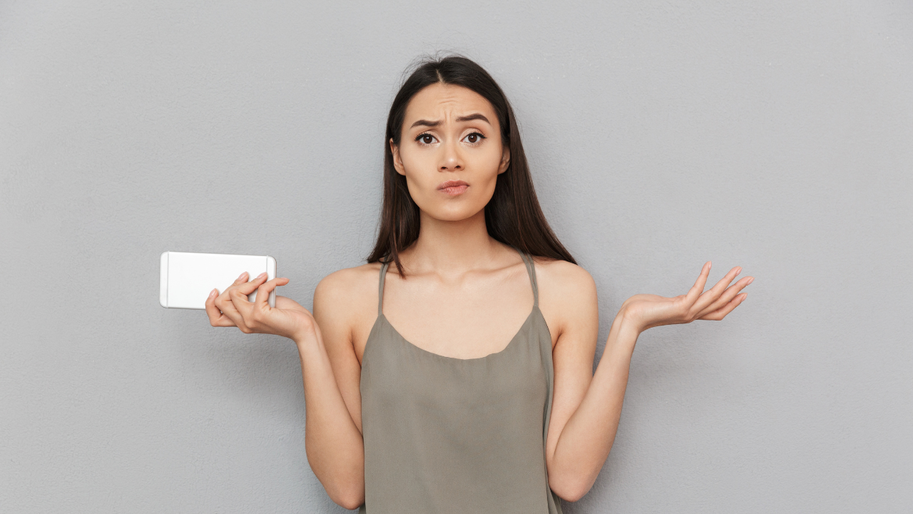 Confused client shrugging with a phone in hand—uncertain about booking policies or forms, a clear red-flag moment to screen.