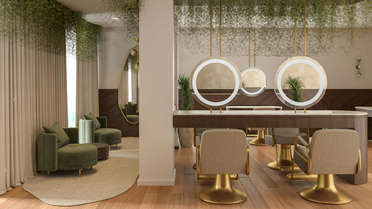 Modern salon with sage lounge chairs, circular lighted mirrors, gold accents, wood floors, and greenery ceiling decor.