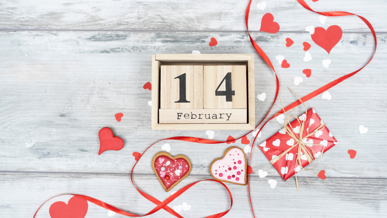 Valentine’s Day February 14 wooden calendar with red ribbon, heart confetti, and gift box on rustic gray wood background.