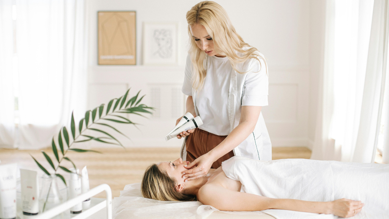 Beauty professional demonstrates gentle aftercare steps while treating a client lying on a spa bed.