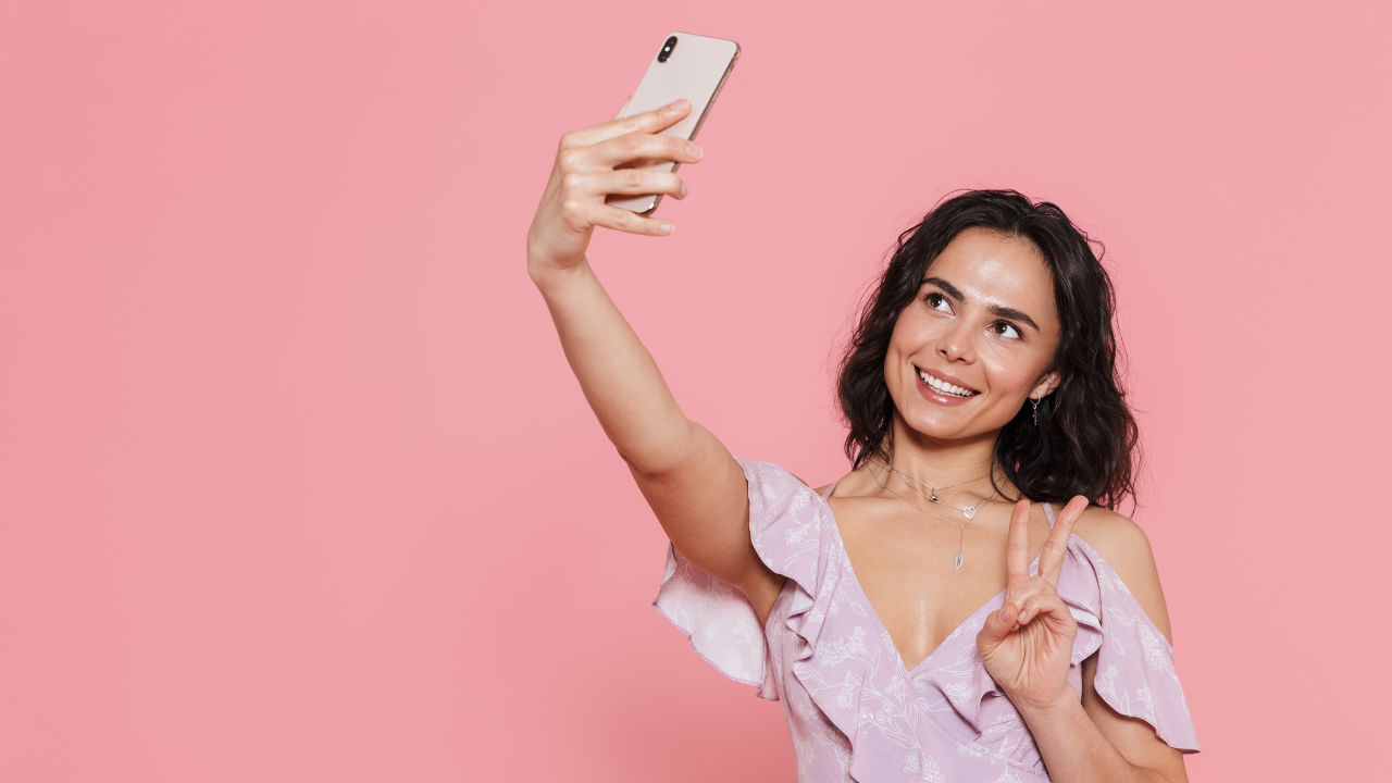 Client taking a quick selfie at a salon’s photo wall after an appointment