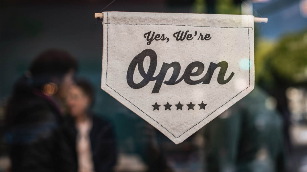 A welcoming “Yes, We’re Open” sign on a small beauty studio, symbolizing a solo owner starting out.