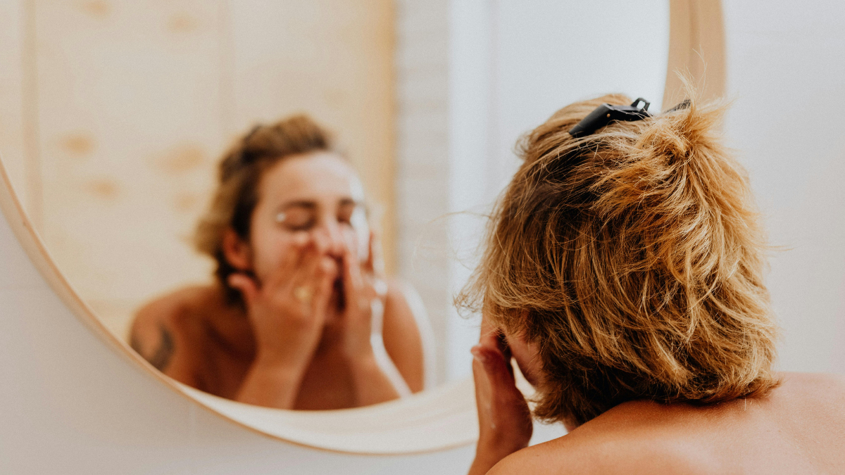 Person washing face gently at sink with clean towel nearby