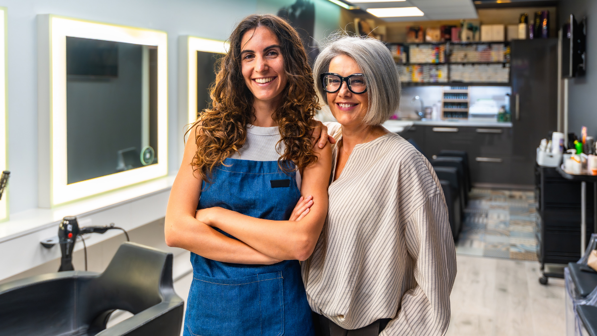 Two smiling salon owners standing together in a modern beauty salon